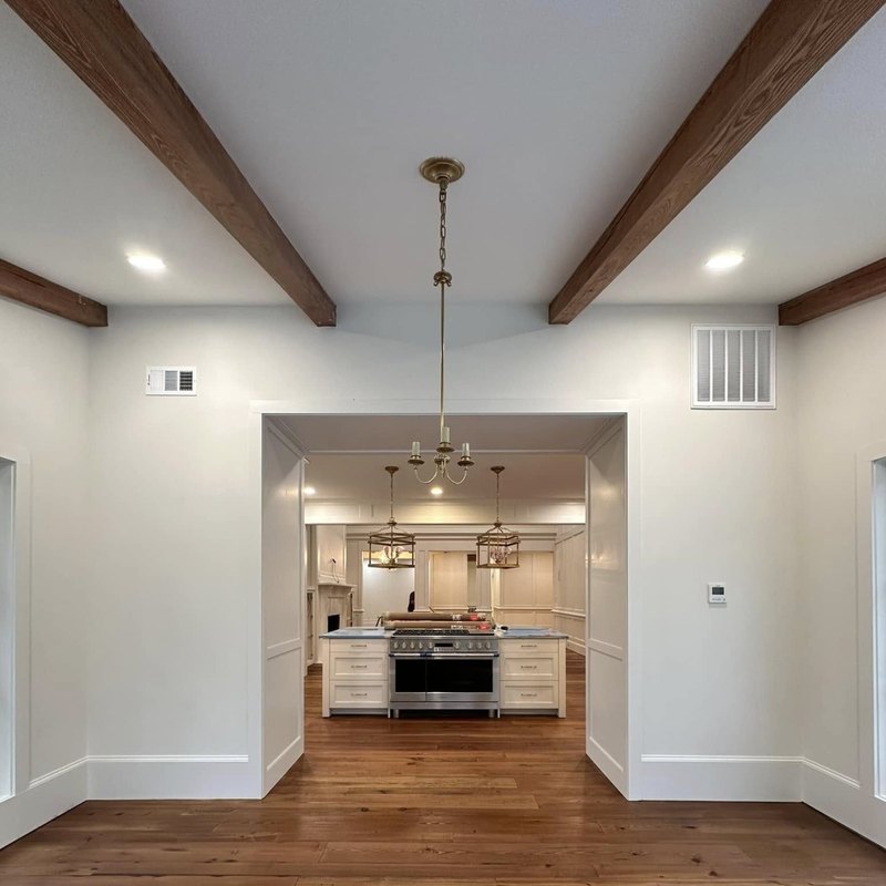 Dining room with a brass chandelier beside a white kitchen