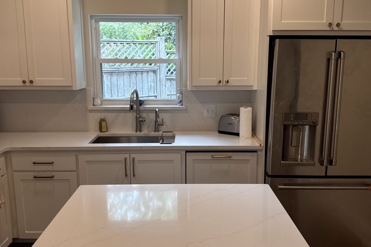 Remodeled white kitchen across a large quartz island