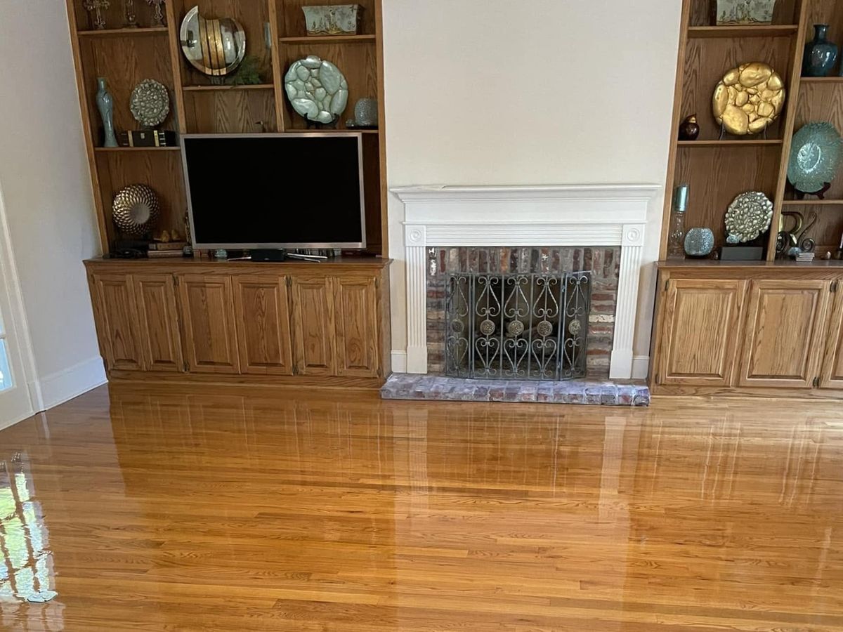 Glossy red oak floor in front of built-in shelves and a white fireplace