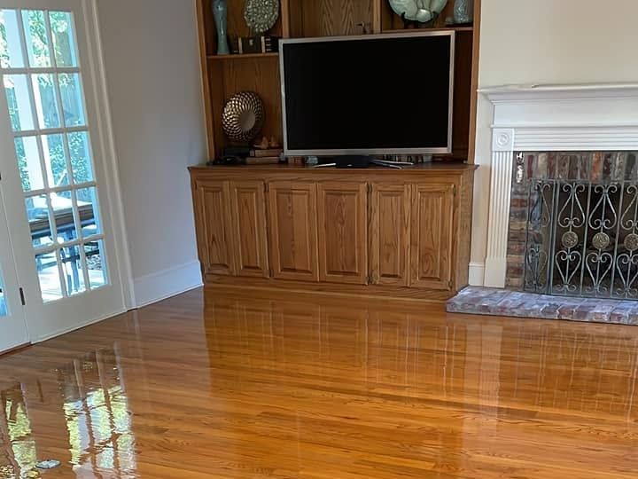 Glossy oak floor reflecting light by a white fireplace and built-in