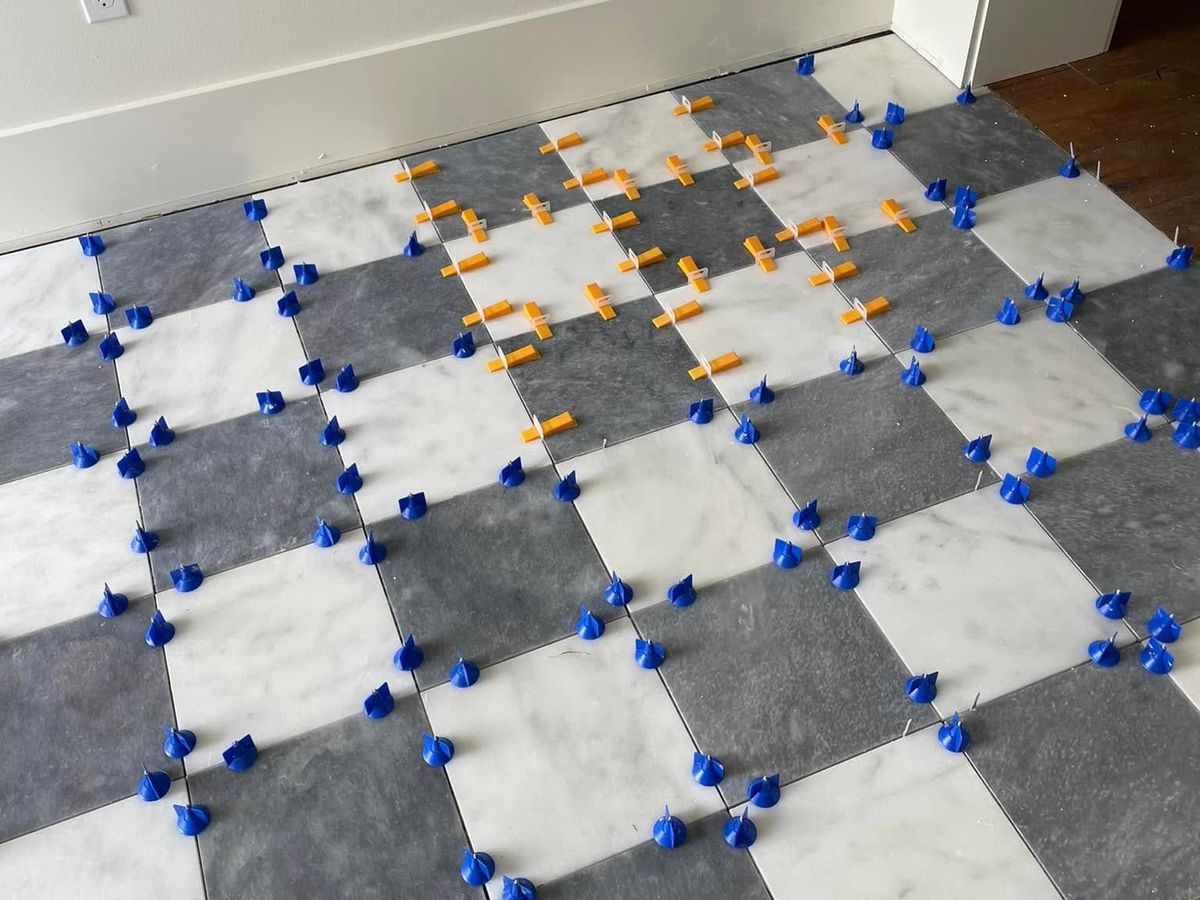 Checkerboard tile going in with leveling clips at every joint