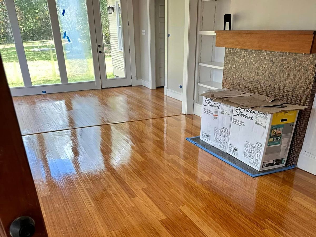 Glossy amber wood floor in front of tall glass doors to a lawn