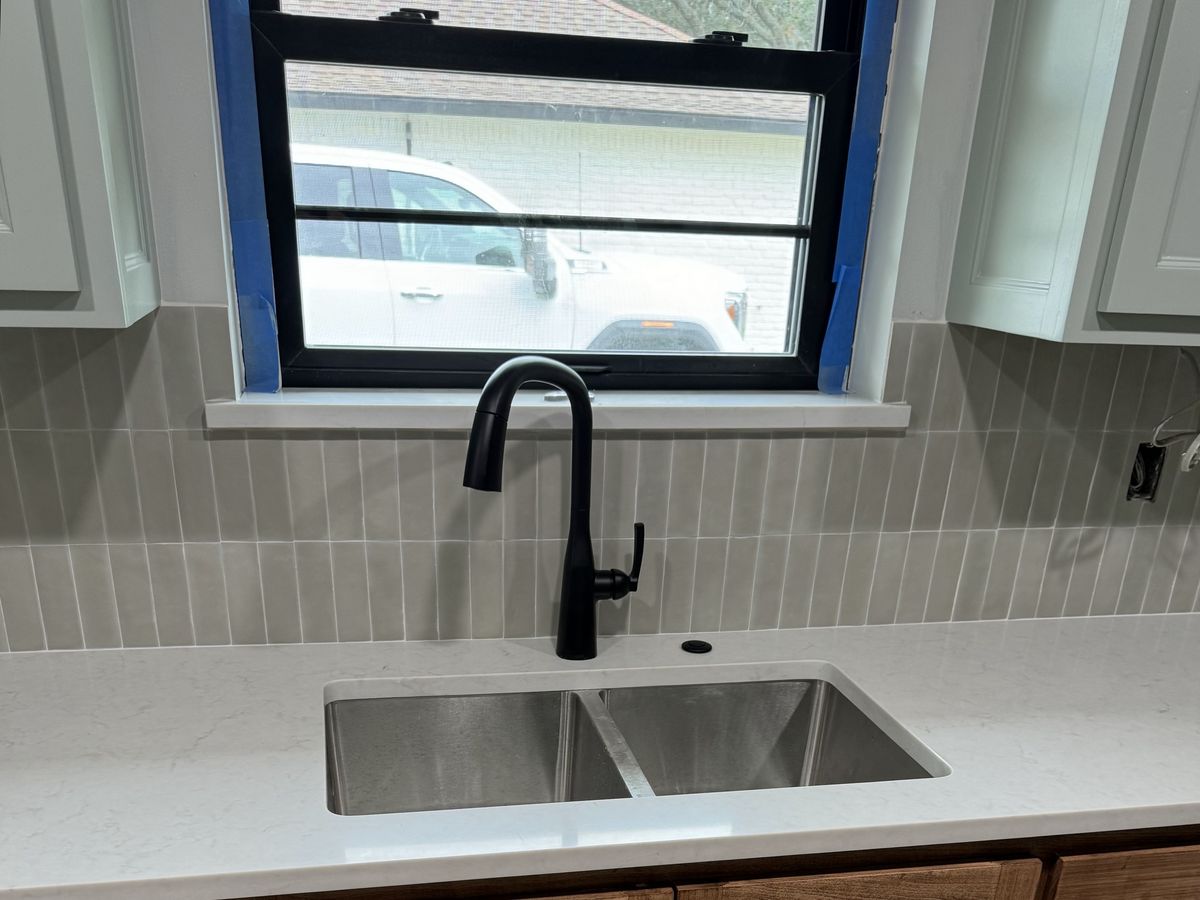 Stainless sink under a black-framed window with gray tile