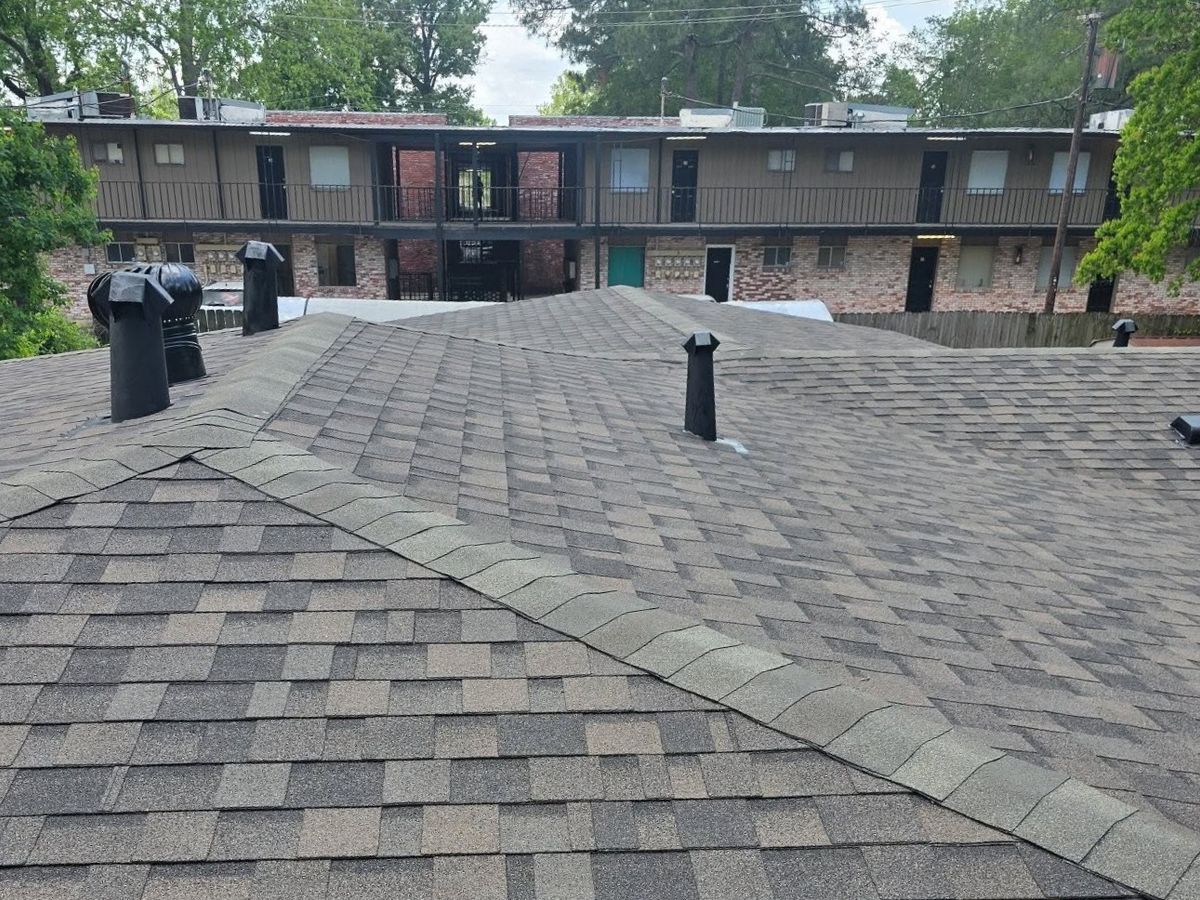 Gray shingle roof seen from above with trees behind