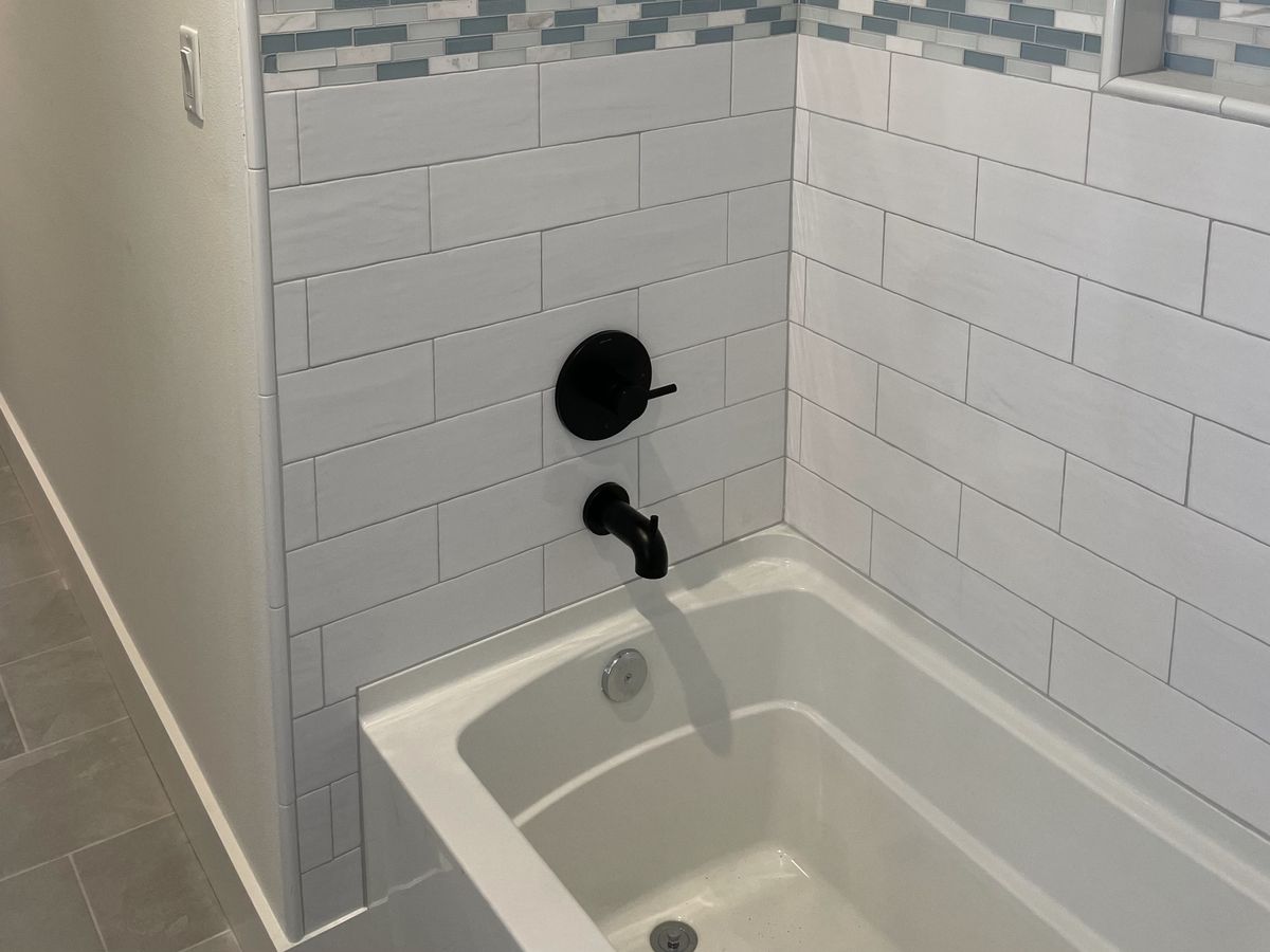 White subway tile shower with a blue glass mosaic band