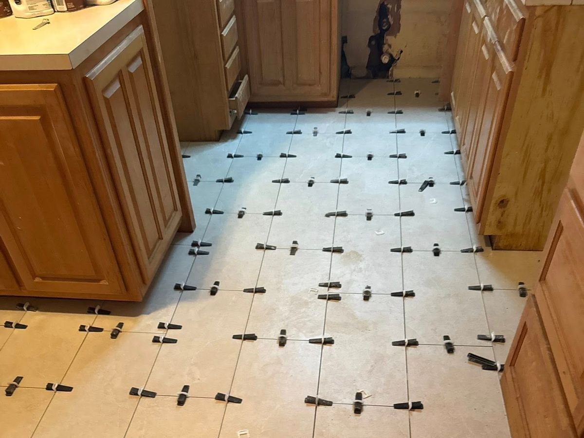 Kitchen floor of large cream porcelain tiles being set