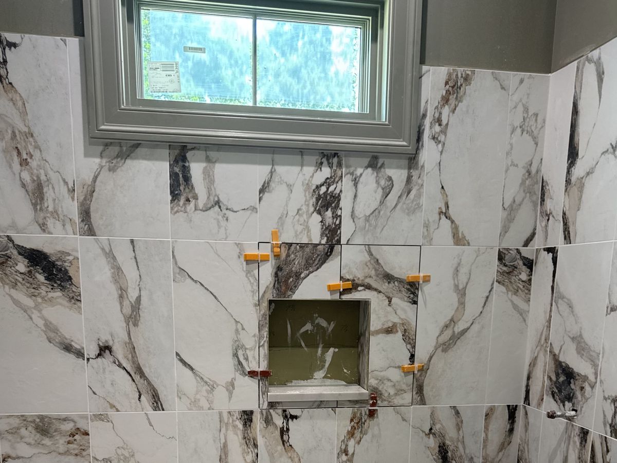 Veined shower tile going up around a recessed niche
