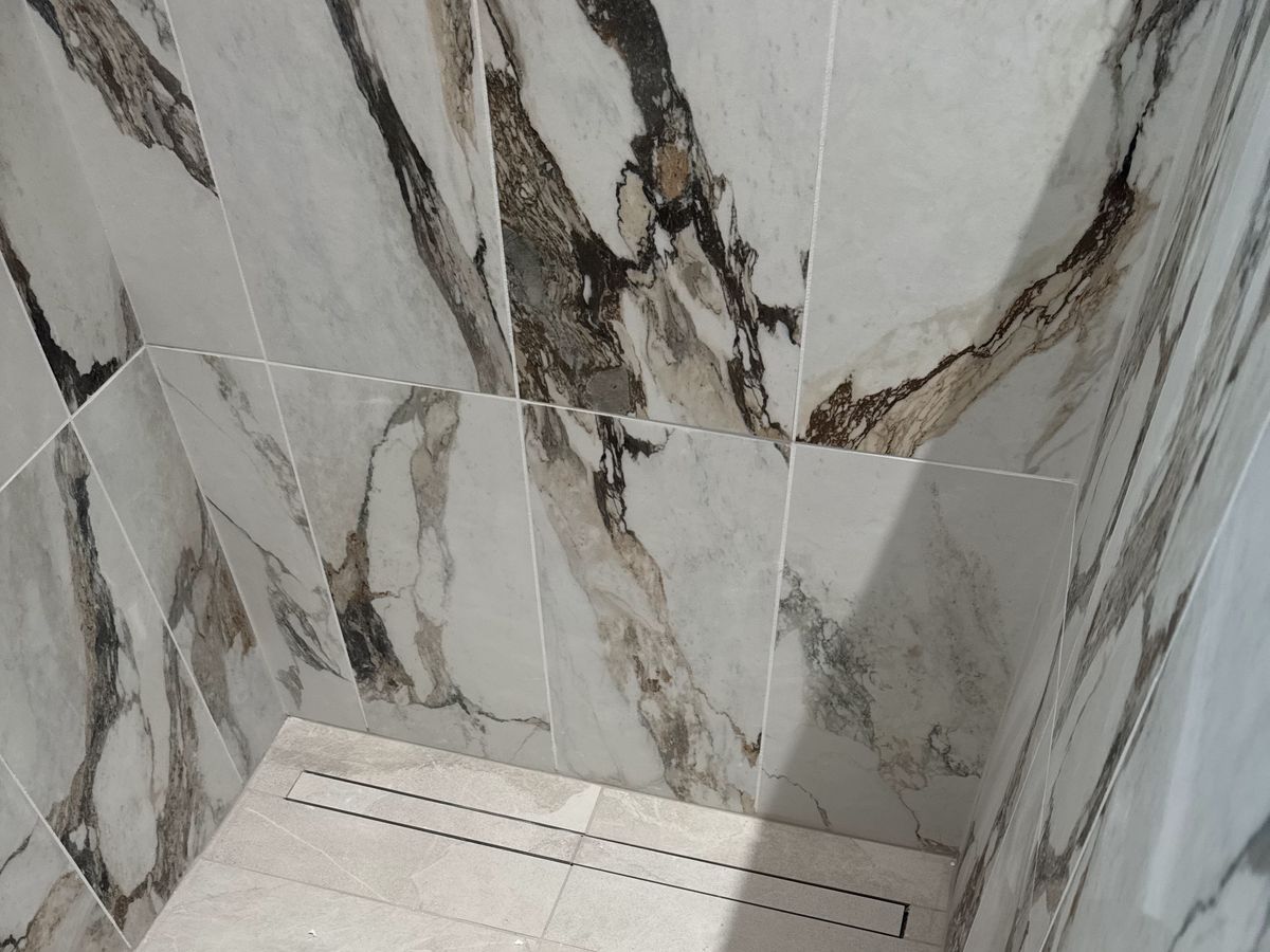 Walk-in shower corner with a long linear drain