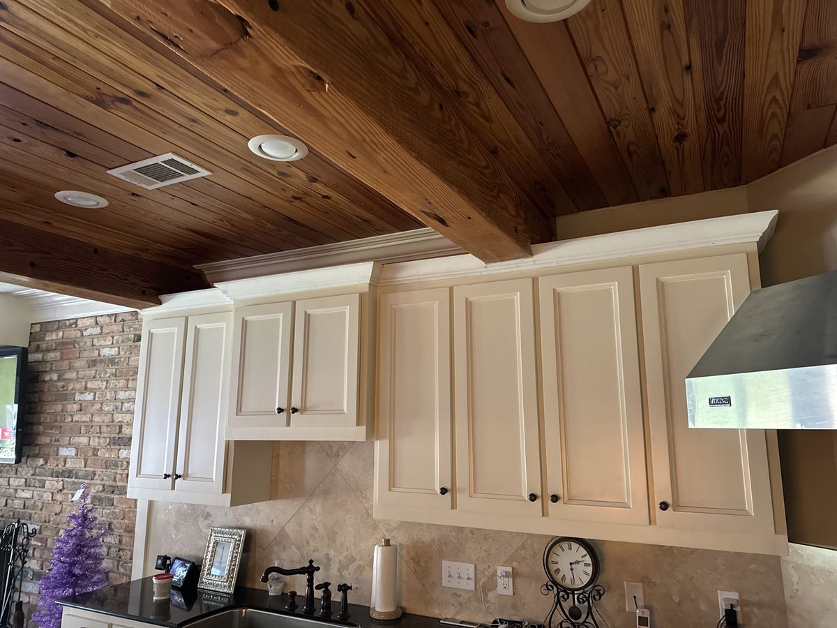 Painted kitchen cabinets by a stone backsplash and brick wall