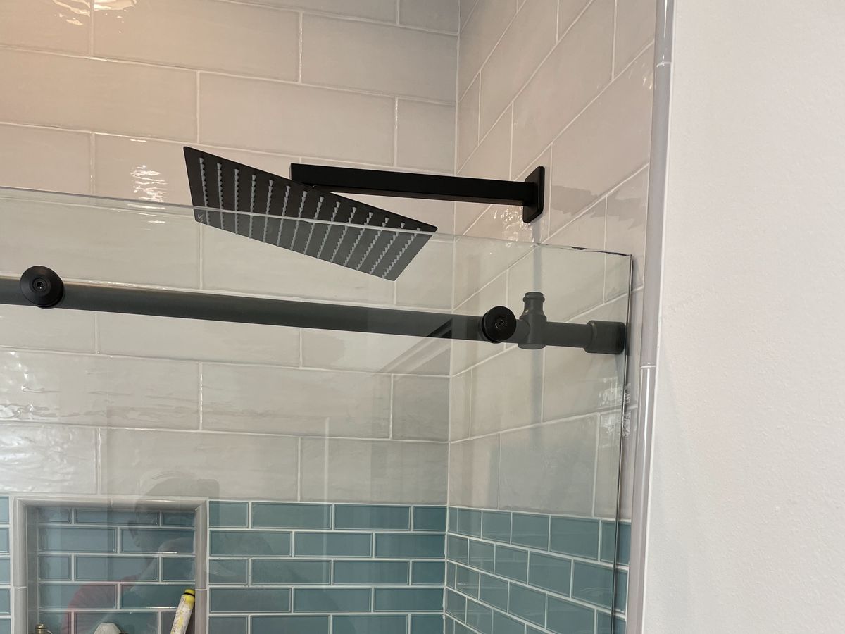 Tiled shower with a rain head behind a frameless sliding door