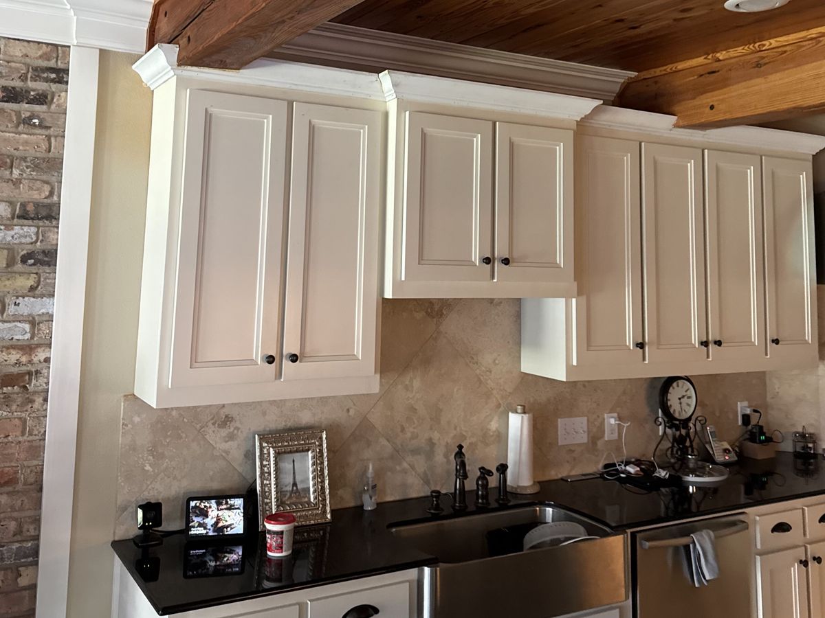 A diagonal stone tile backsplash under cream-painted cabinets