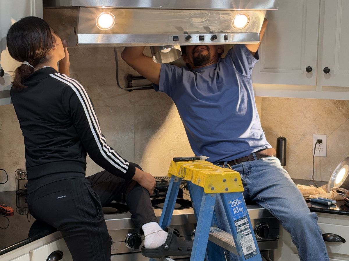 Kitchen hood install with one worker on a blue ladder