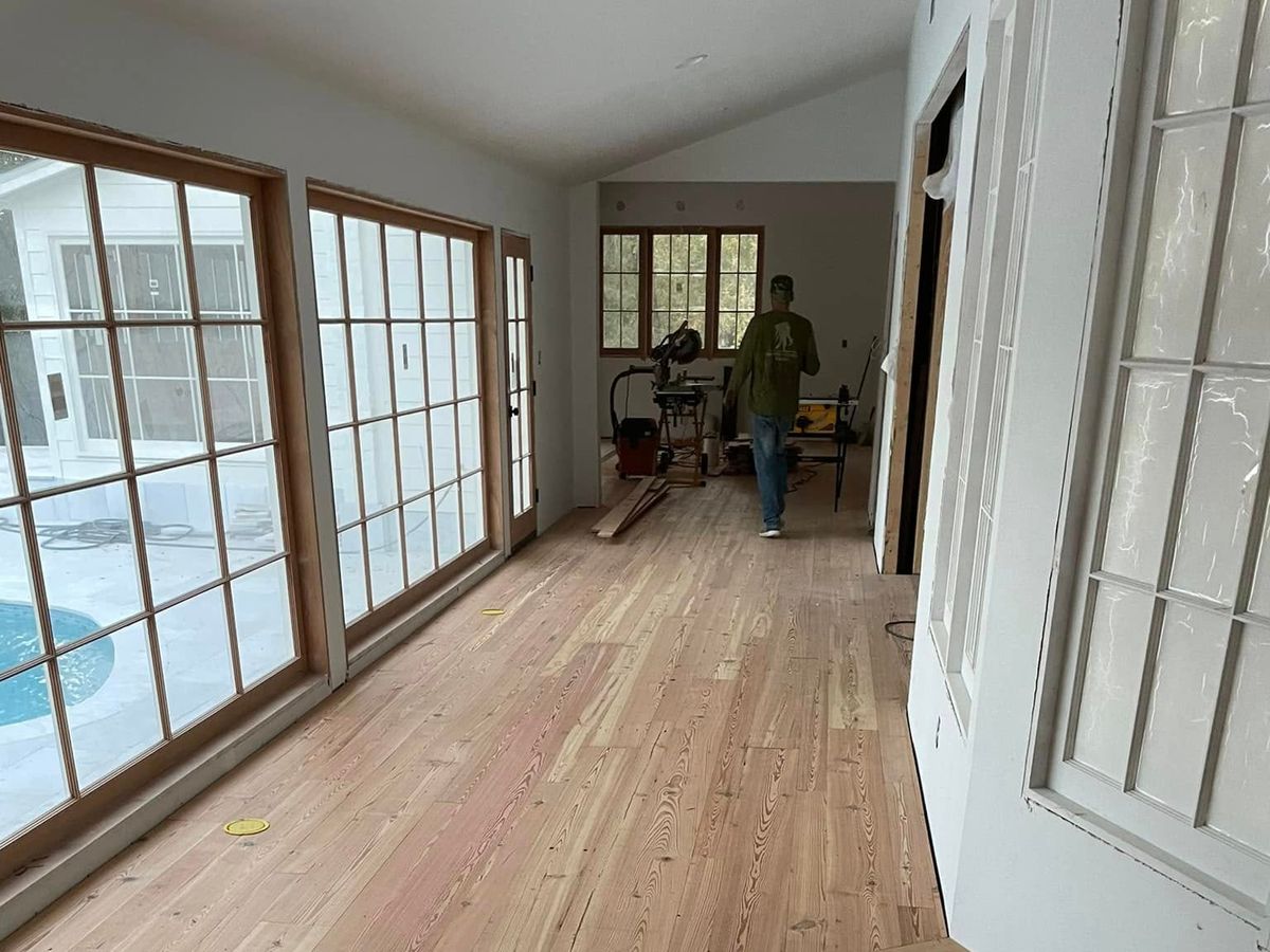 Fresh pine floor install in a sunroom of tall windows by a pool