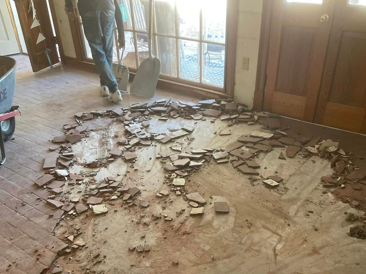 Old terracotta floor tile being torn out of a room with glass doors
