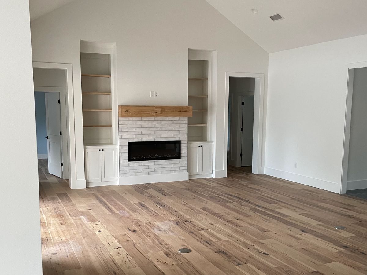 Great room with a vaulted white ceiling and wide-plank floors