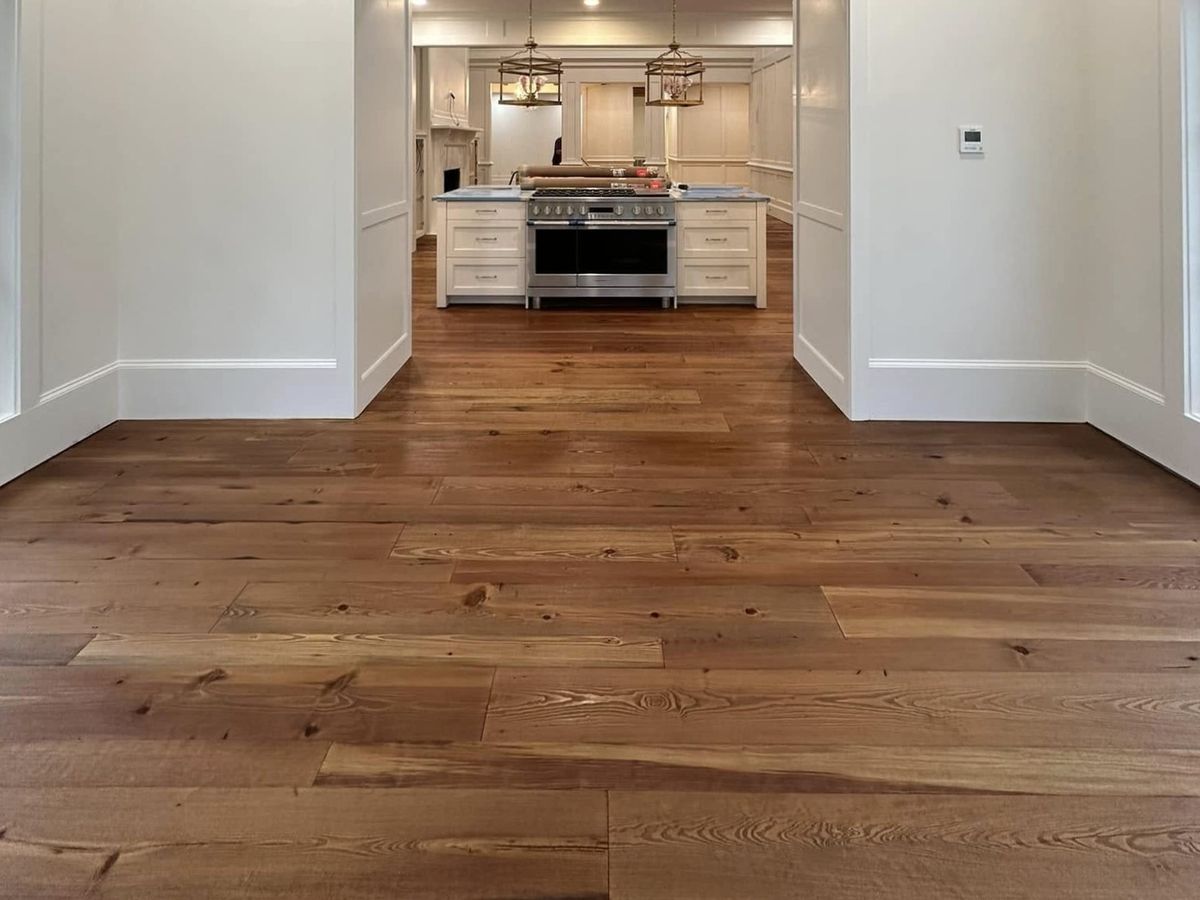 Renovated dining room under stained beams opening to a white kitchen