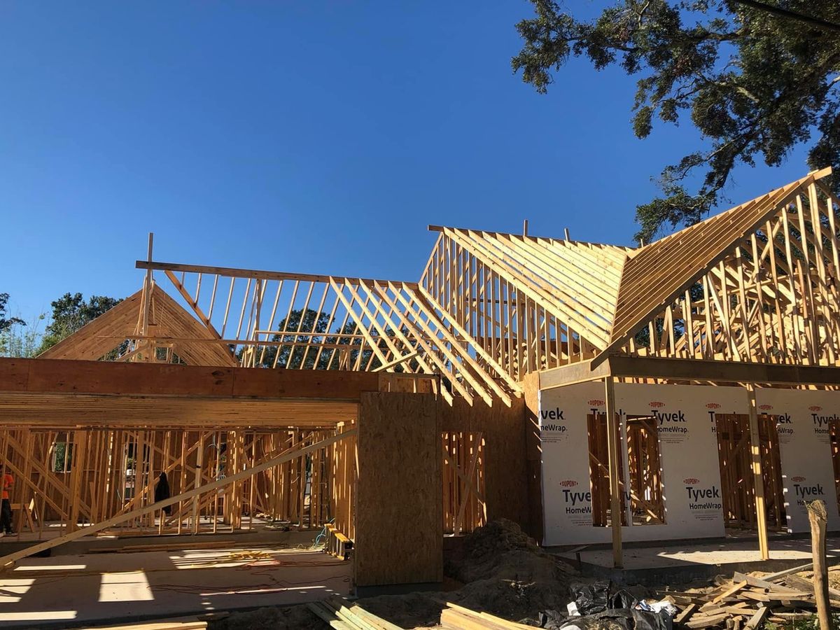 Large new house in framing with an open-trussed roof and porch beam