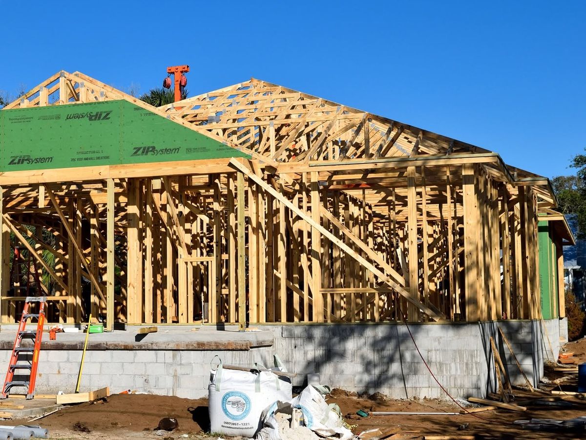 Open stud walls and roof trusses on a block foundation, with the gable sheathed