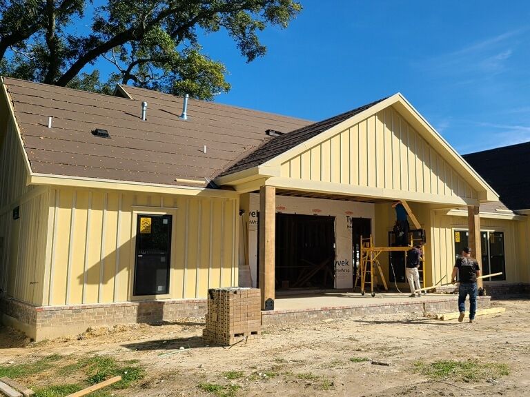 New home with a brown shingle roof and a brick skirt