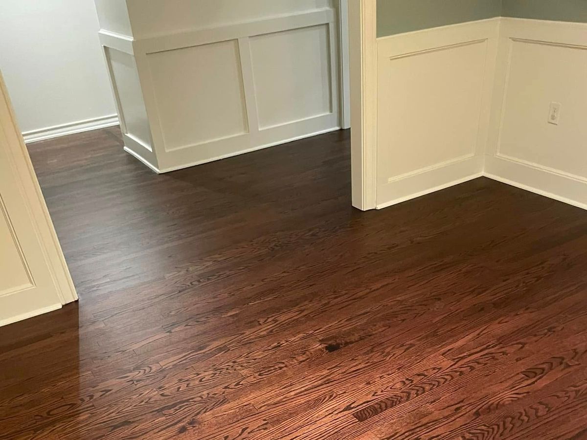Finished dark-stained oak floor beside white paneling and trim