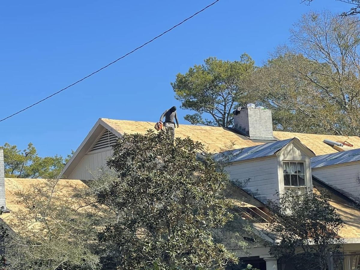 Roof decking beside a gray metal roof section on a white house