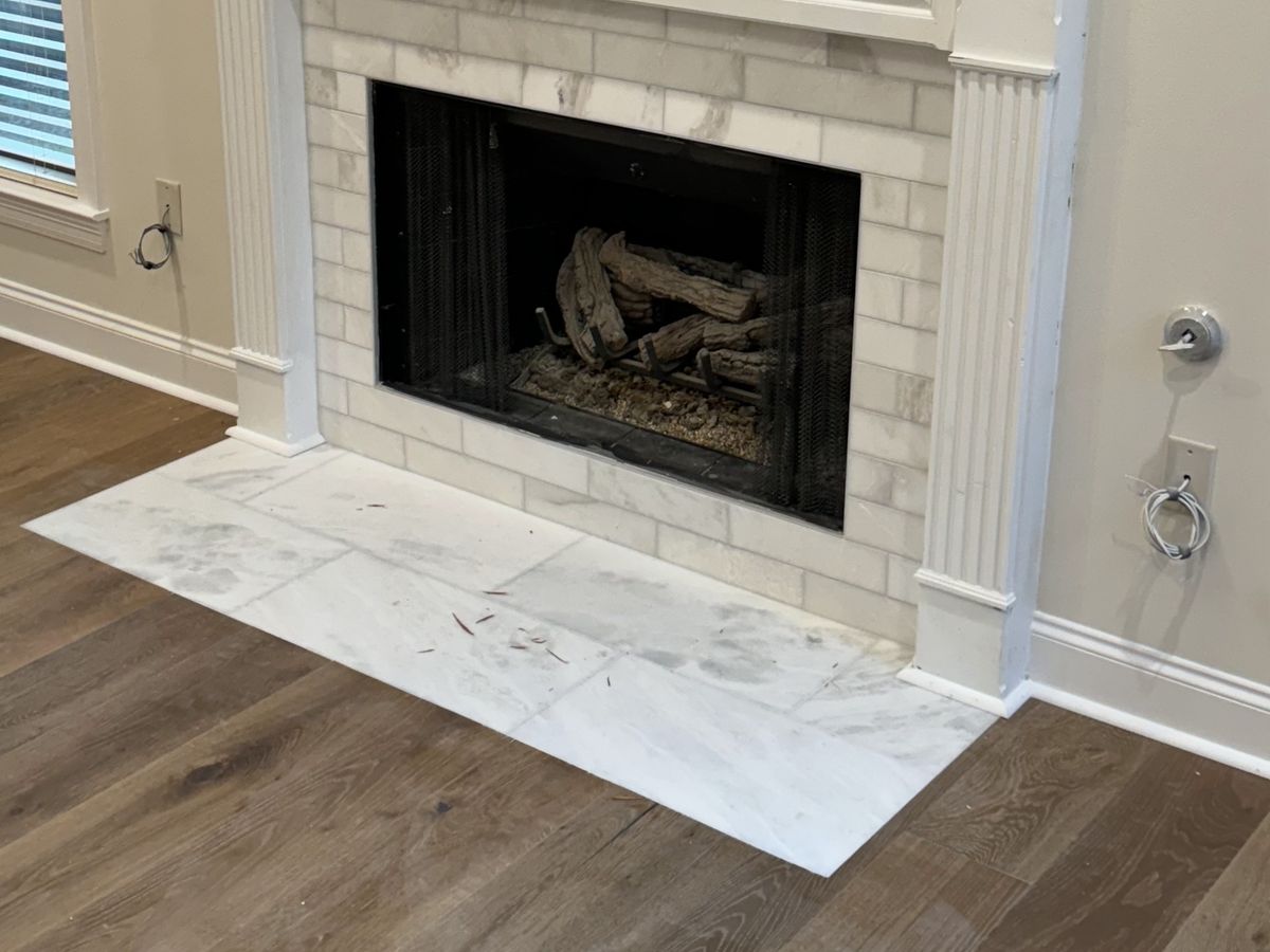New white marble tile surround and hearth on a wood-look floor
