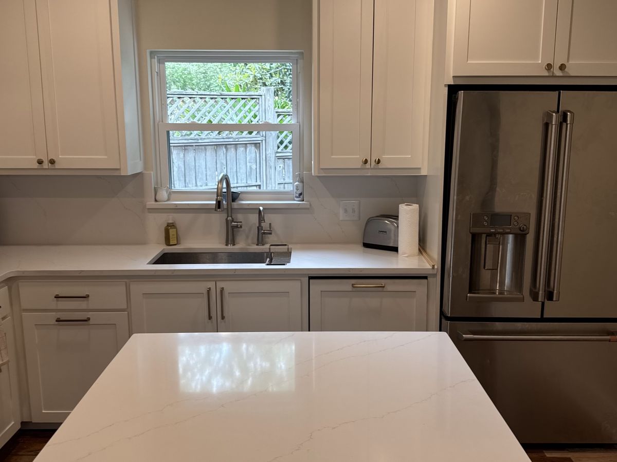 Remodeled white kitchen across a large quartz island