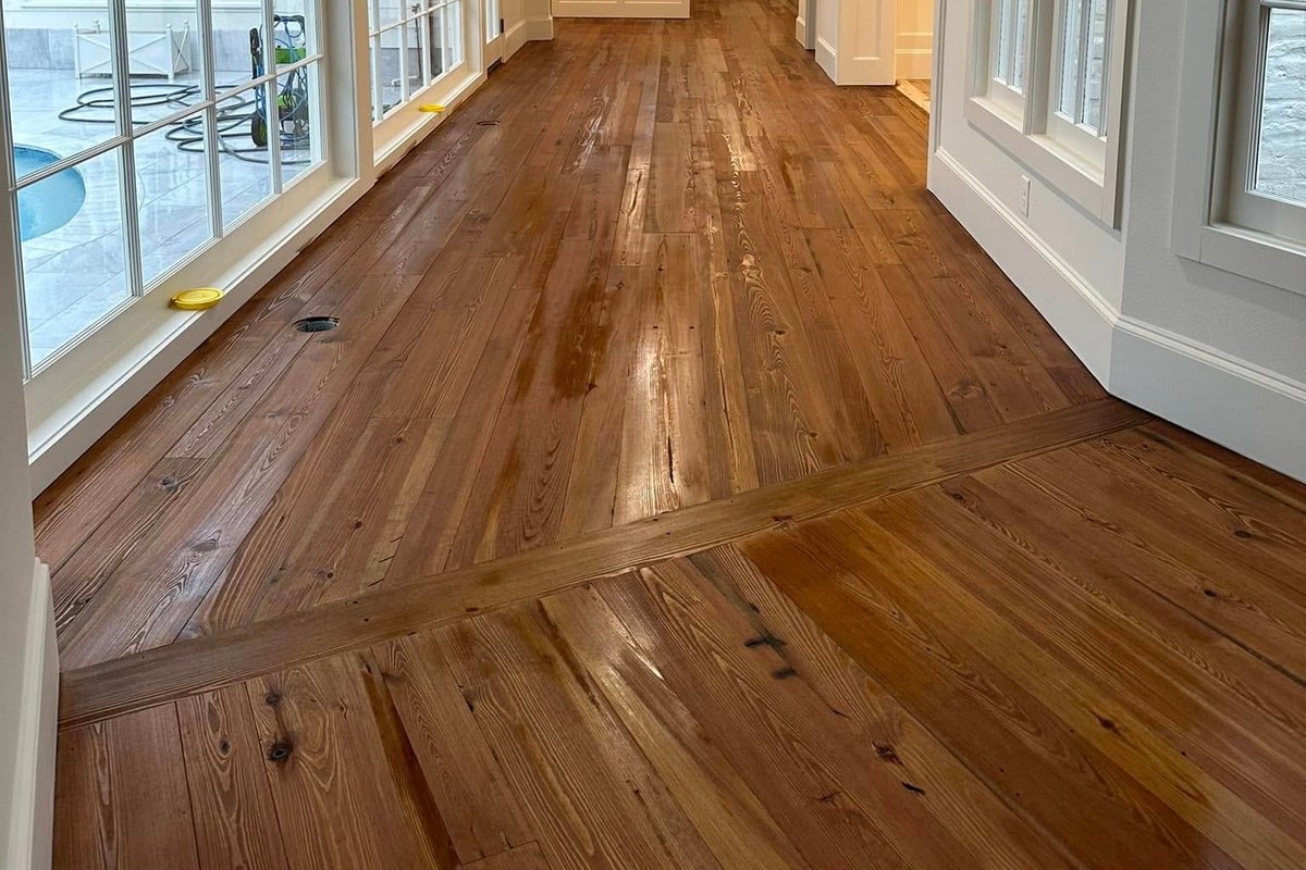 A finished amber heart pine floor under dark wood beams