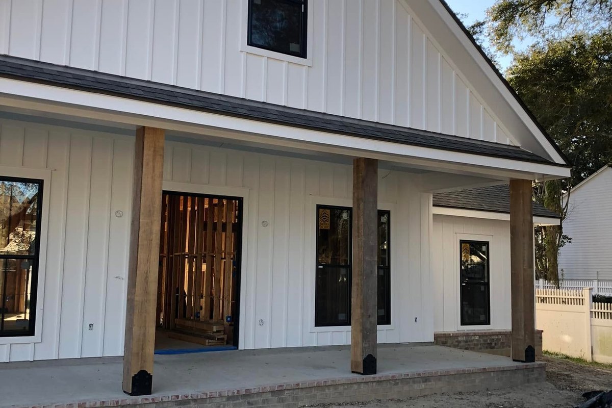Front of a new white home with a steep gable and black-framed window