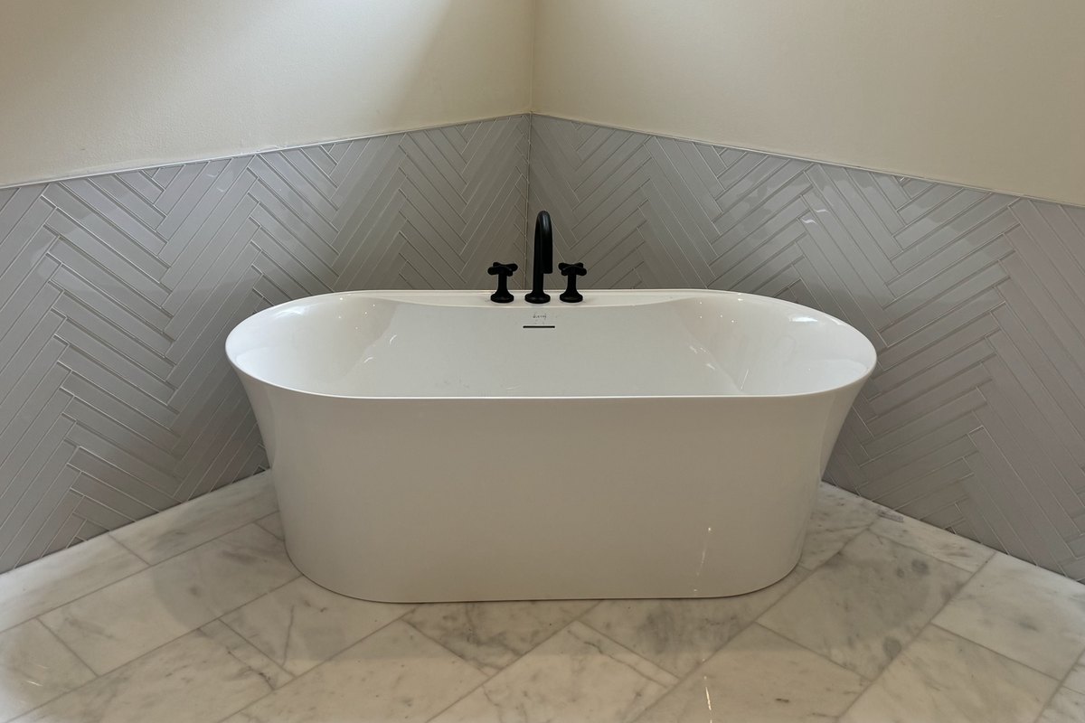 Freestanding white soaking tub with a black wall faucet
