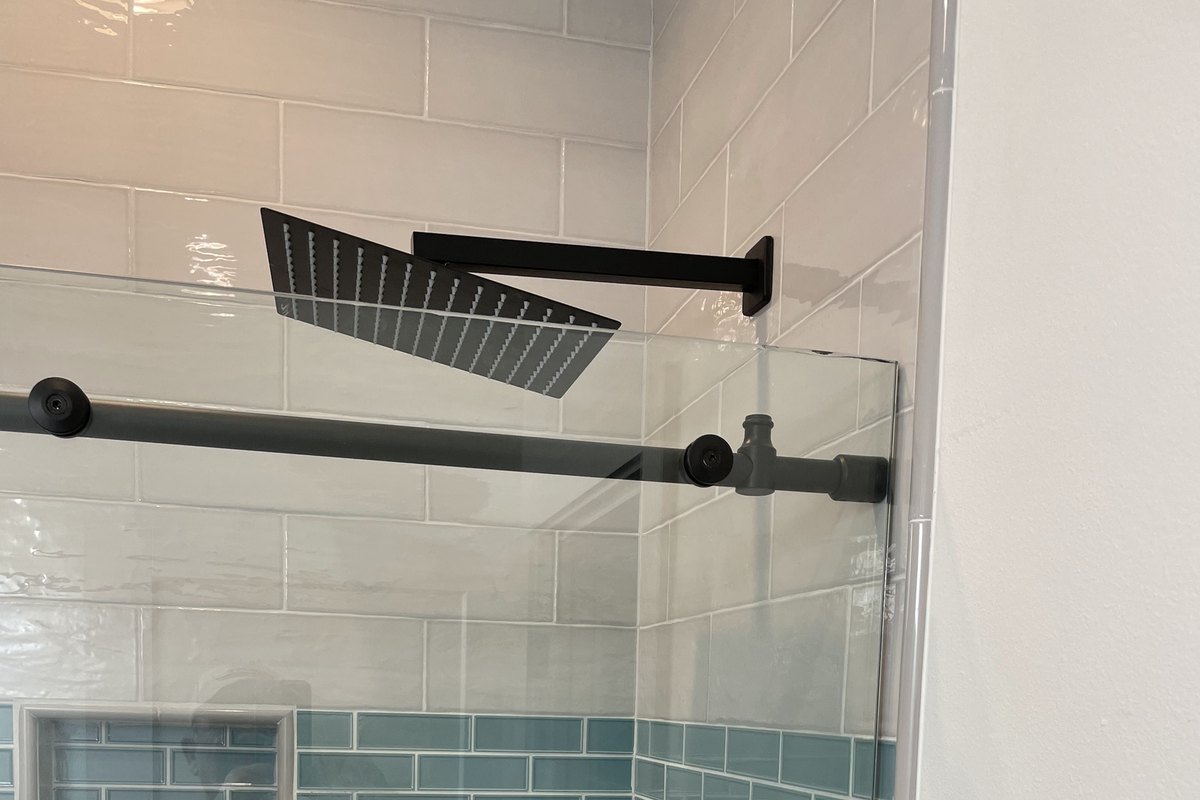 Walk-in shower in glossy white subway tile with an aqua band