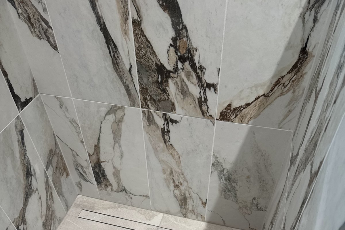 Finished walk-in shower with large marble-look wall tile