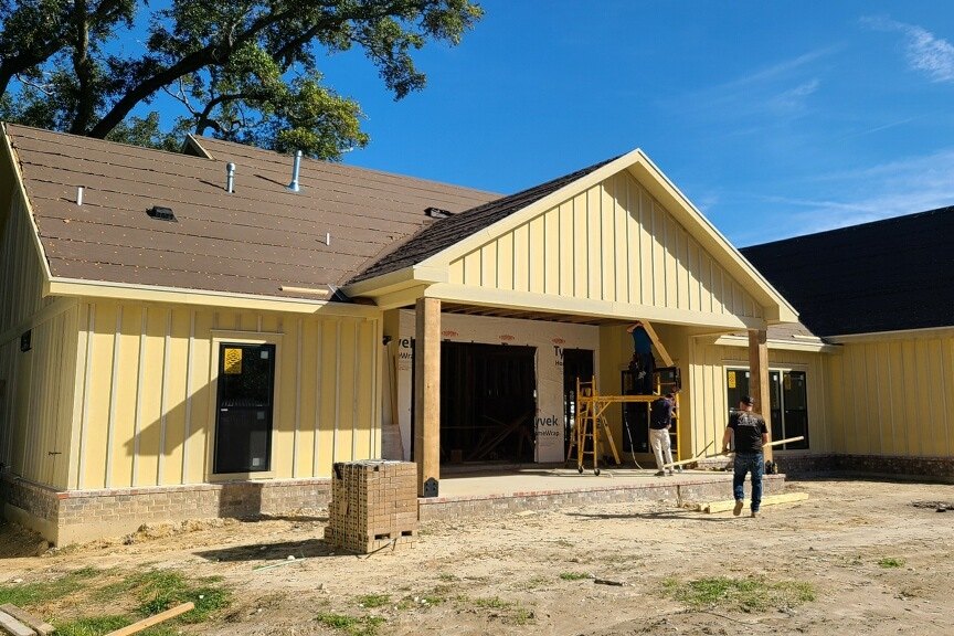 Brown shingle roof going on a new pale yellow farmhouse