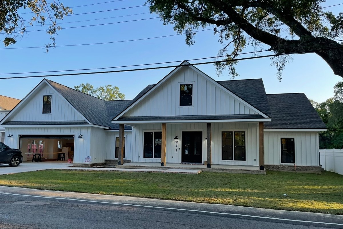 Street view of a white modern farmhouse with a charcoal roof