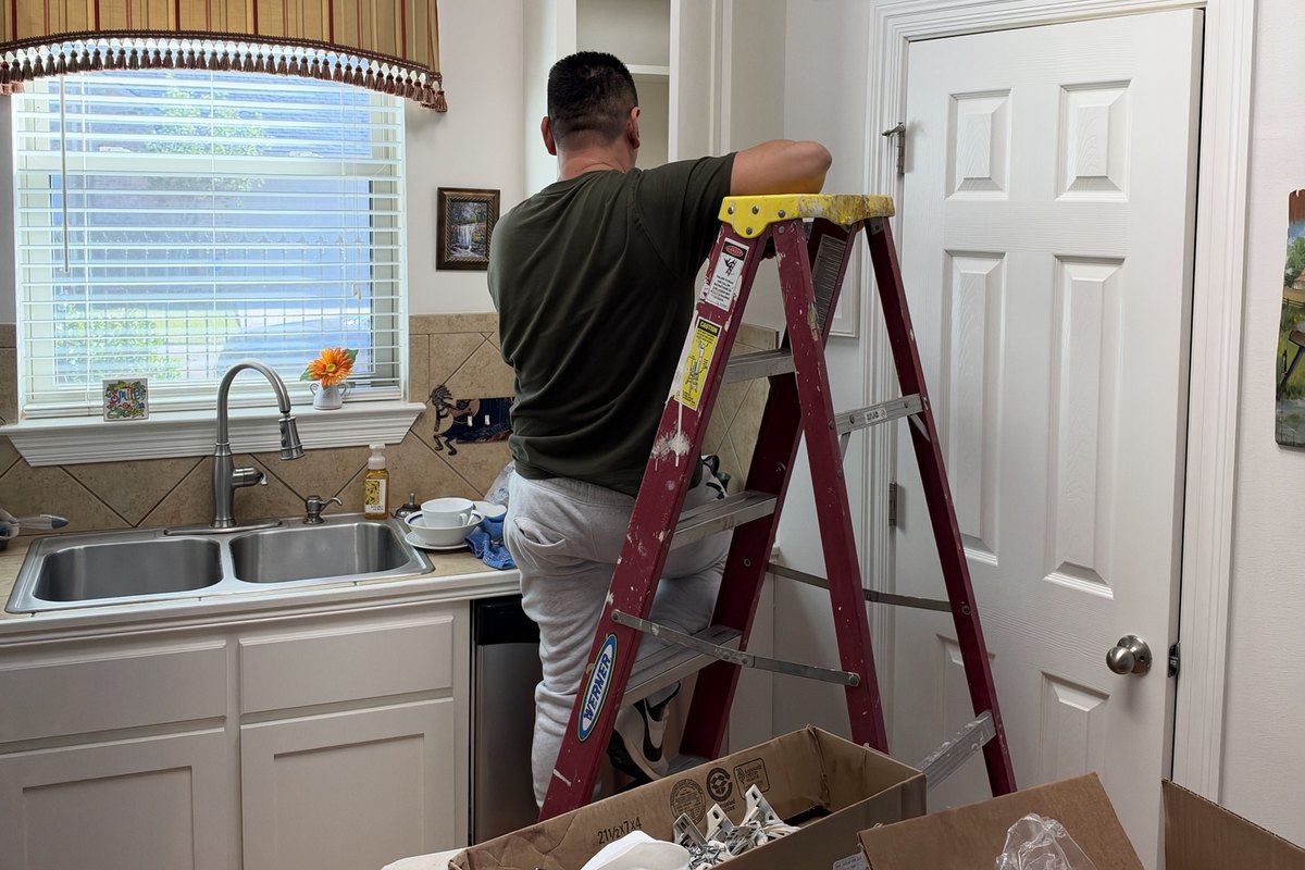 White kitchen cabinet top being fitted by a worker