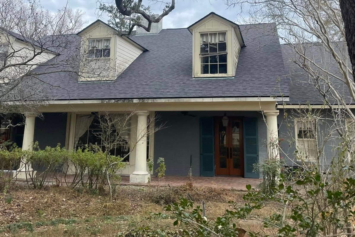 New dark charcoal shingle roof on a gray Acadian-style house