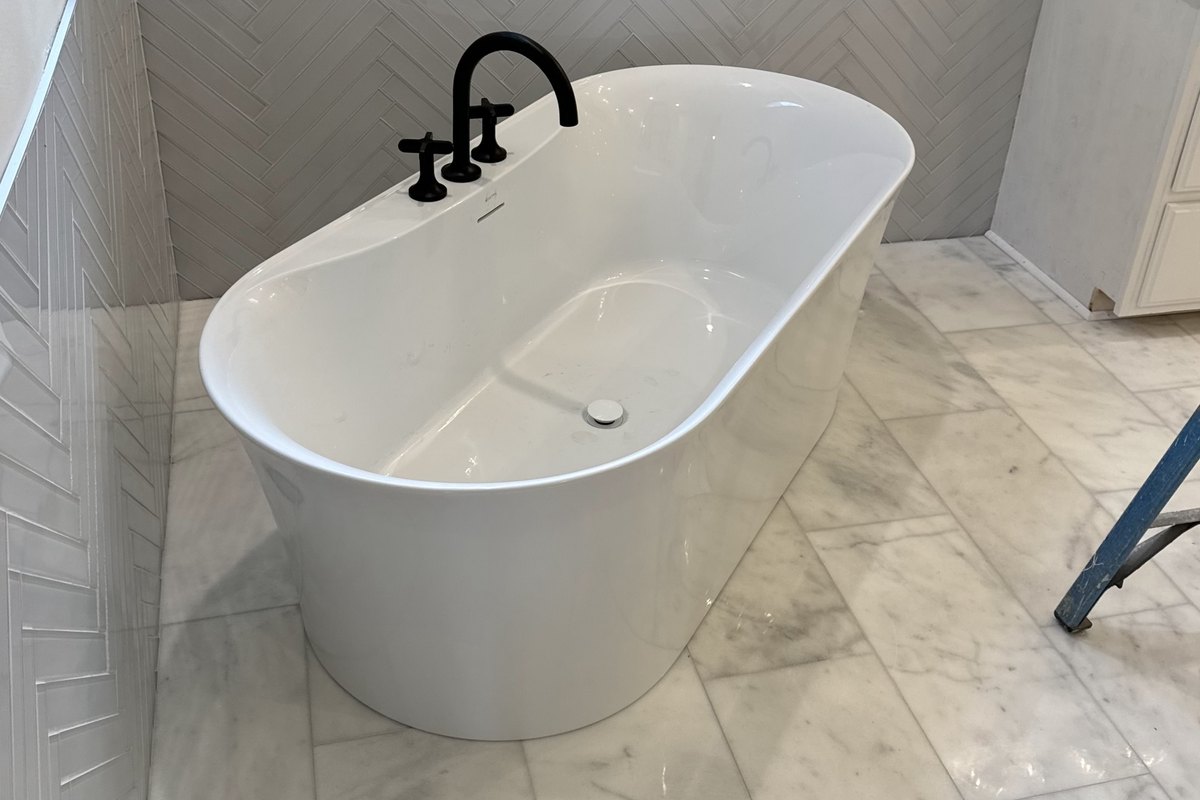 White freestanding oval soaking tub with a black faucet