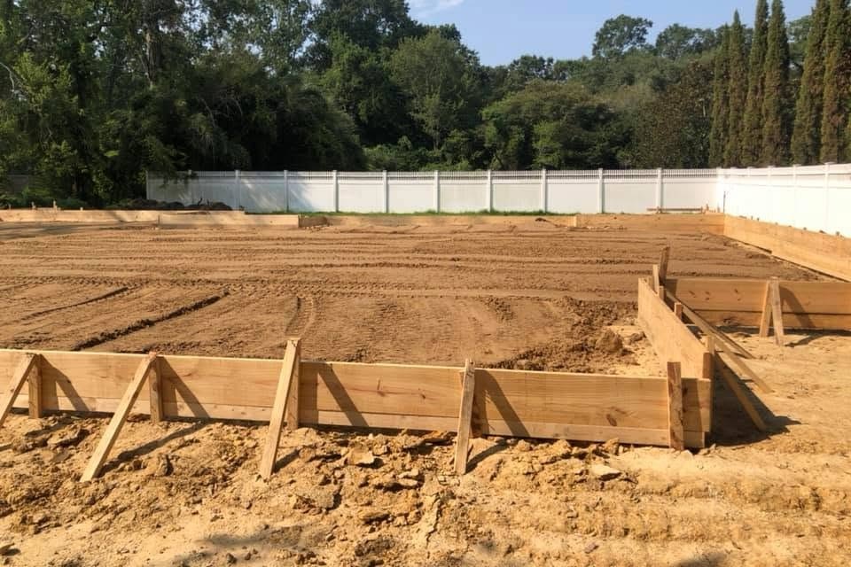 Wide view of a lot readied for a new home, tire tracks in tan dirt