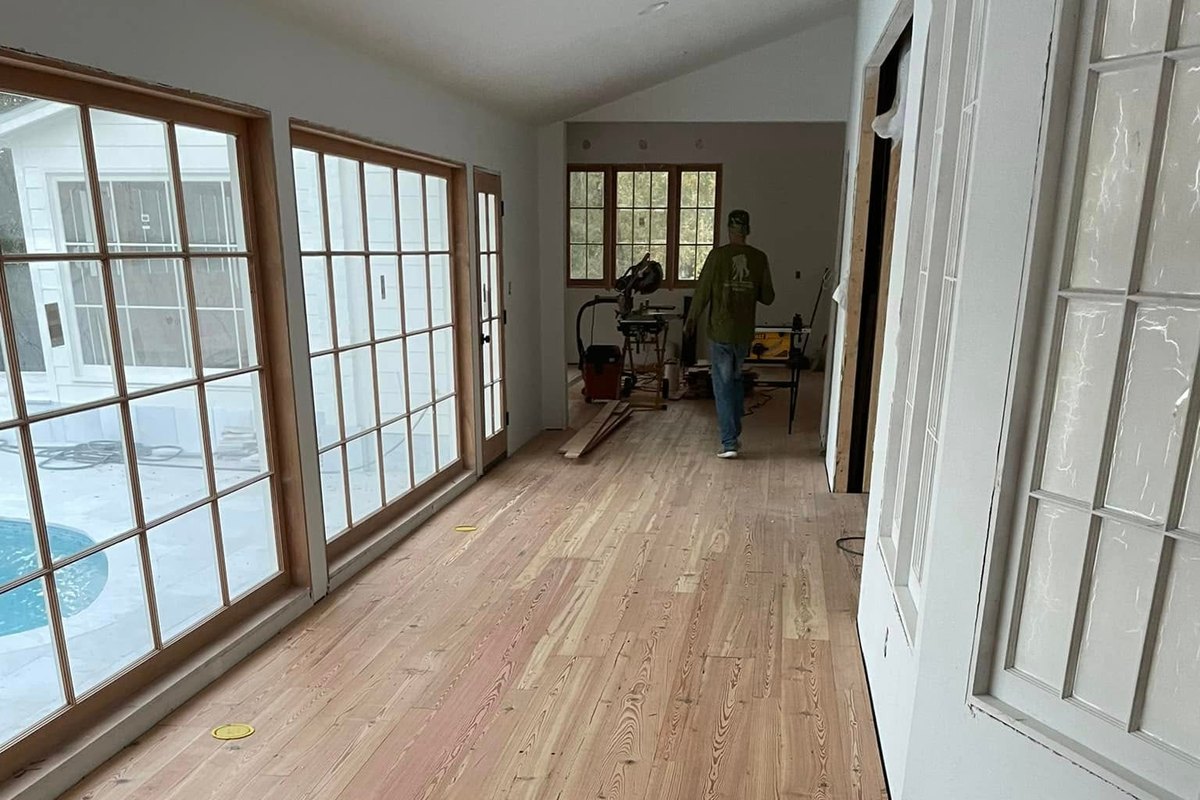 Long sunroom with a newly laid unfinished pine floor and a border