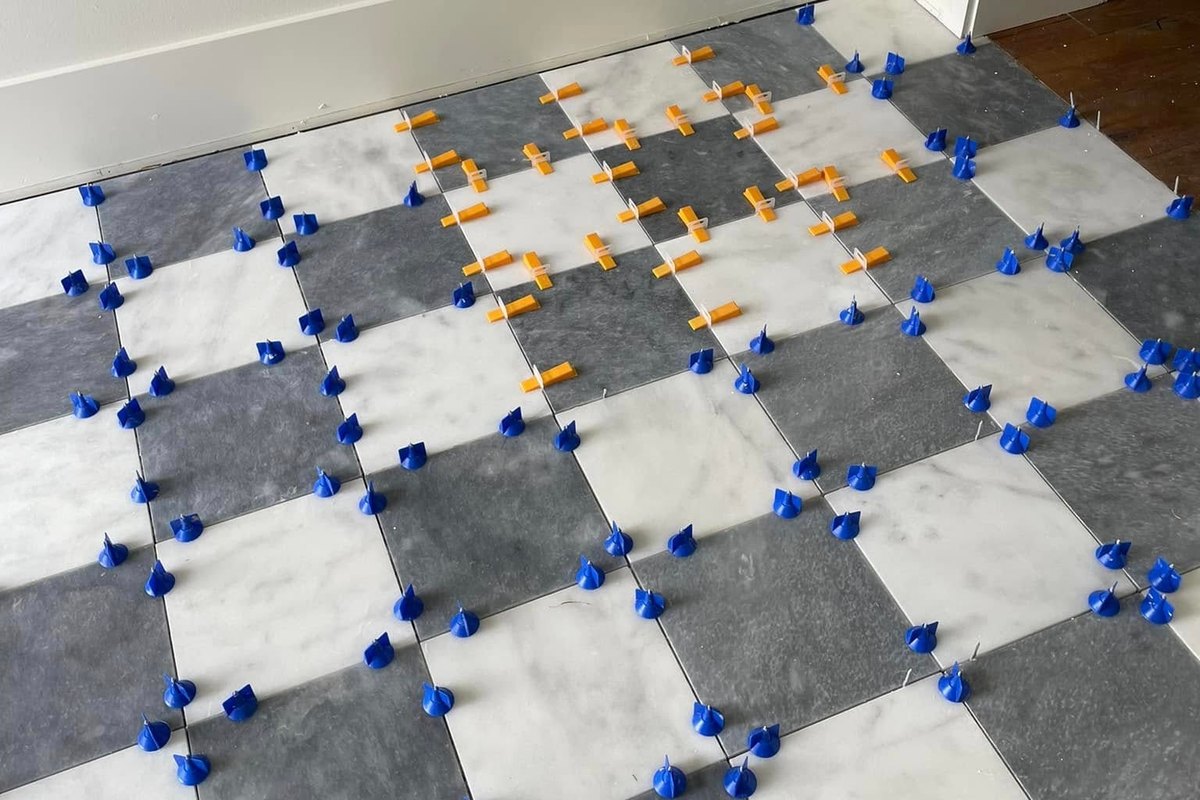 White and gray marble tile being set in a diagonal checkerboard