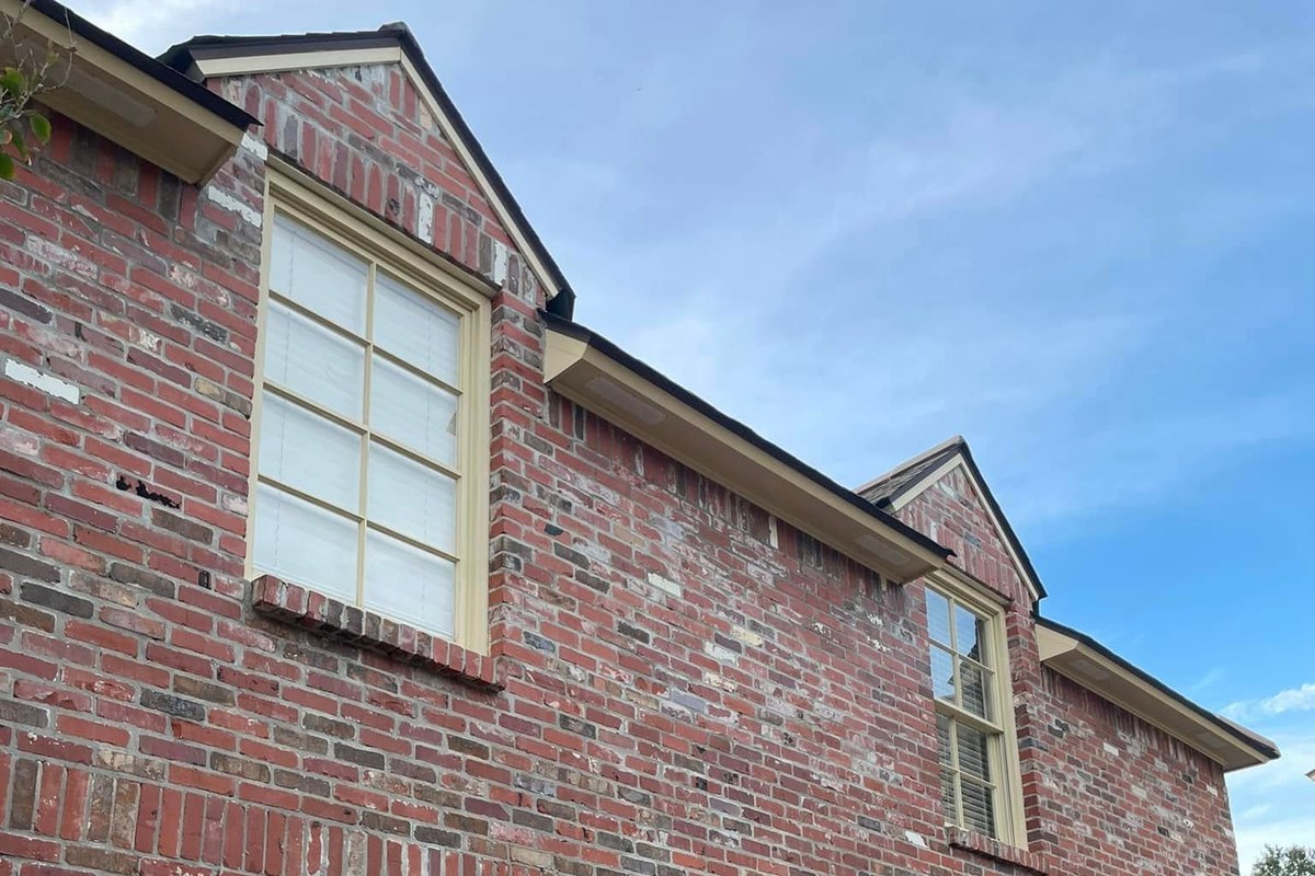 Red brick wall with two gable windows and cream trim