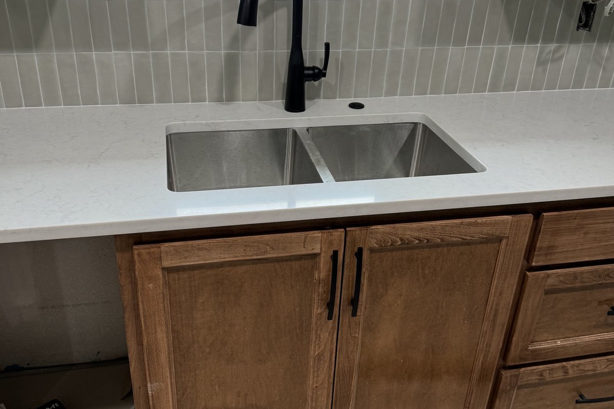 Undermount sink with a black pull-down faucet in a quartz counter