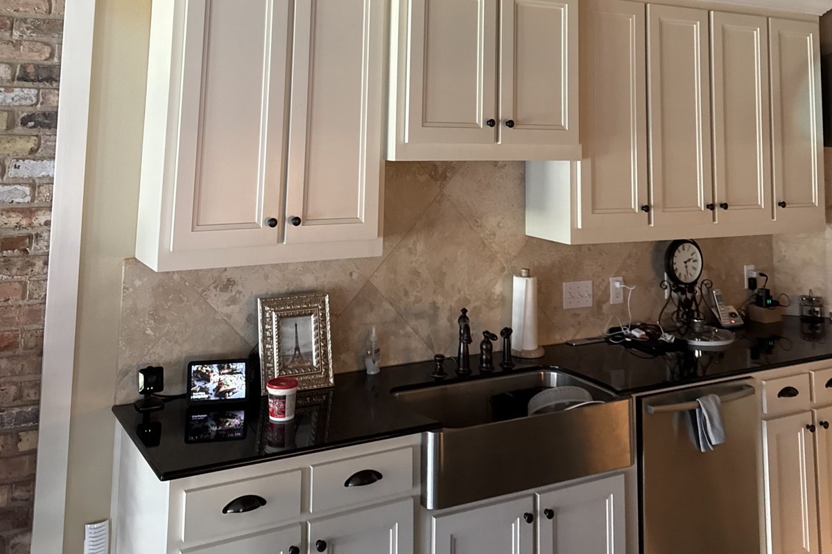 A diagonal stone tile backsplash under cream-painted cabinets