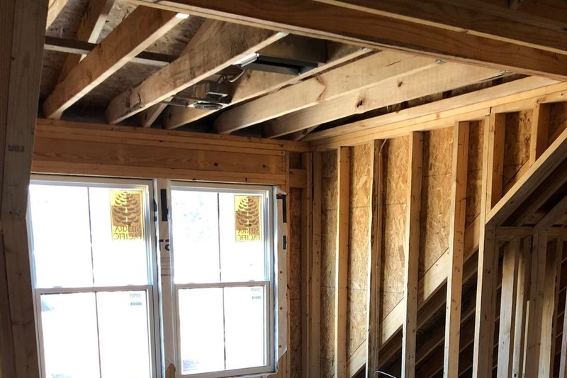 Framed new room with a stair wall and new double-hung windows