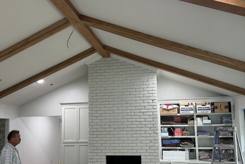 Painted brick fireplace under a vaulted ceiling with beams