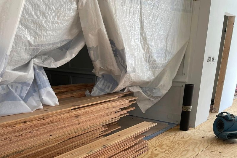 Stacks of unfinished pine floorboards on a plywood subfloor