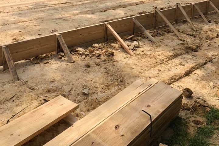 Cleared lot graded for a new slab with fresh lumber stacked in front