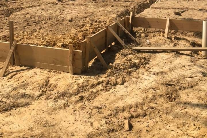 Footing trench dug inside wood slab forms on a graded pad