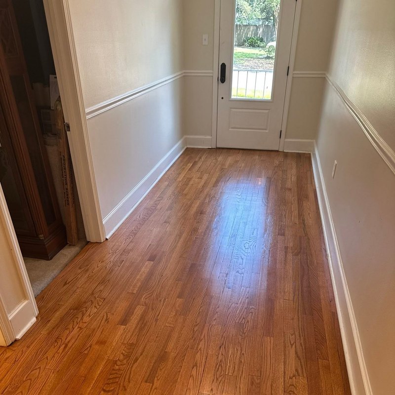 Refinished oak floor running to a white front door