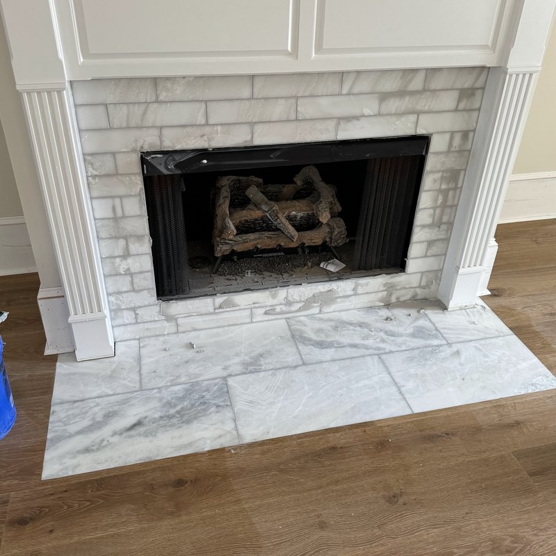 Fireplace surround newly tiled in white marble subway tile